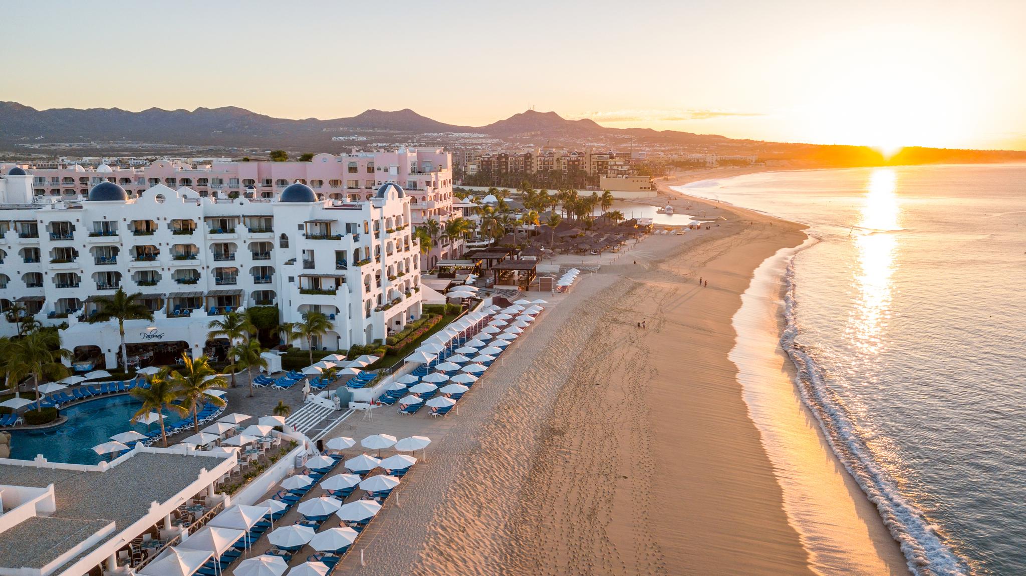 Birdseye view of the sun setting over the resort reflecting off the ocean