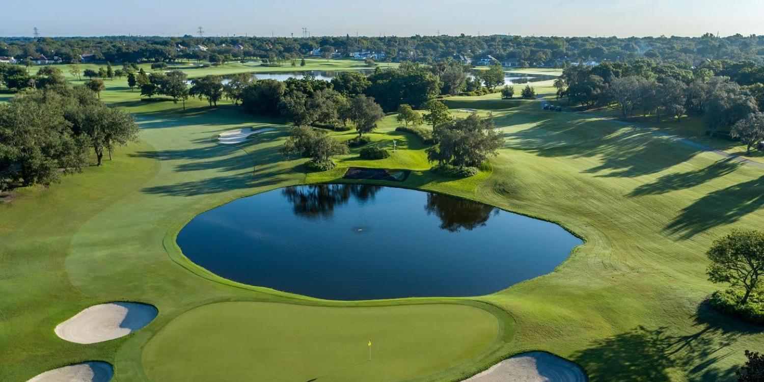 Aerial view of the course with a large pond in the centre surrounded by winding fairways and a smooth green