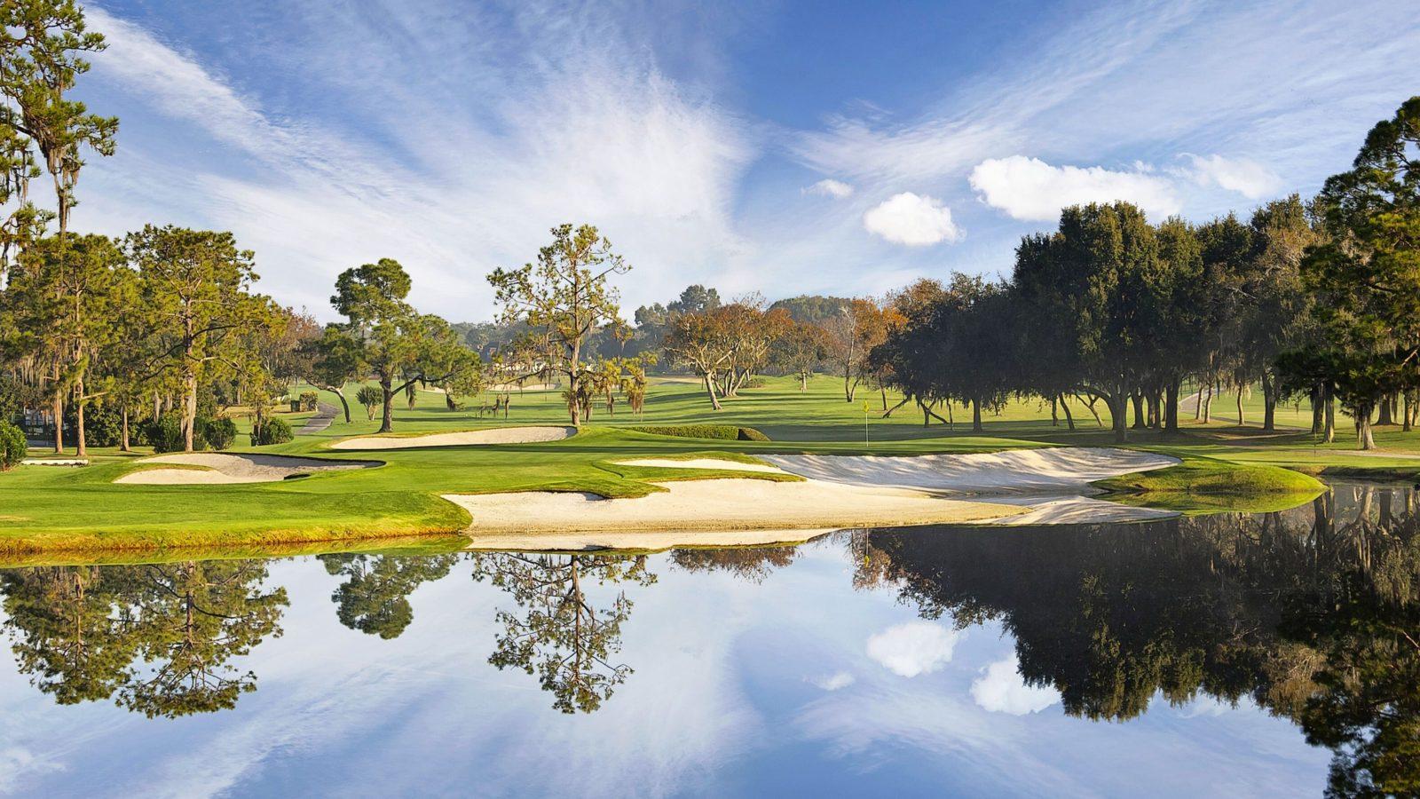 Panoramic view of and bunkers strategically placed next to a water hazard under blue skies