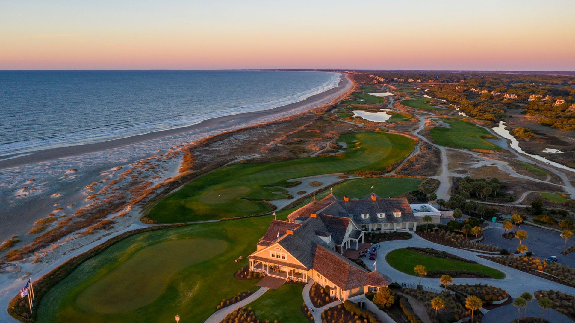 A panoramic view of the course and coastline at sunset, highlighting the clubhouse.