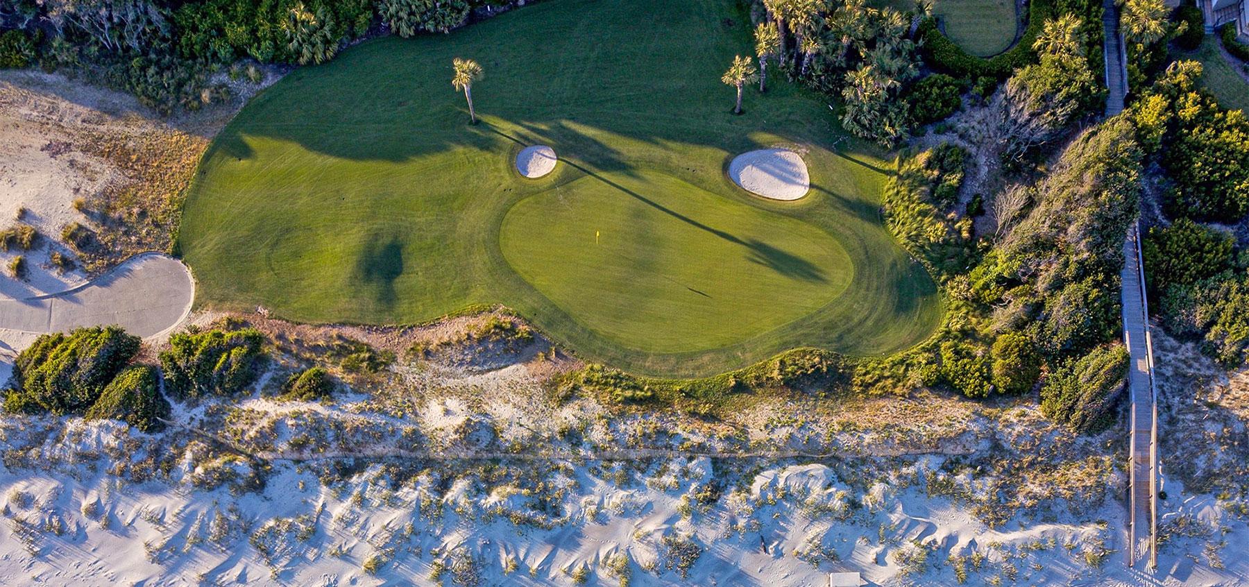 Aerial view of a well-maintained green nestled with two bunkers at the Turtle Point course