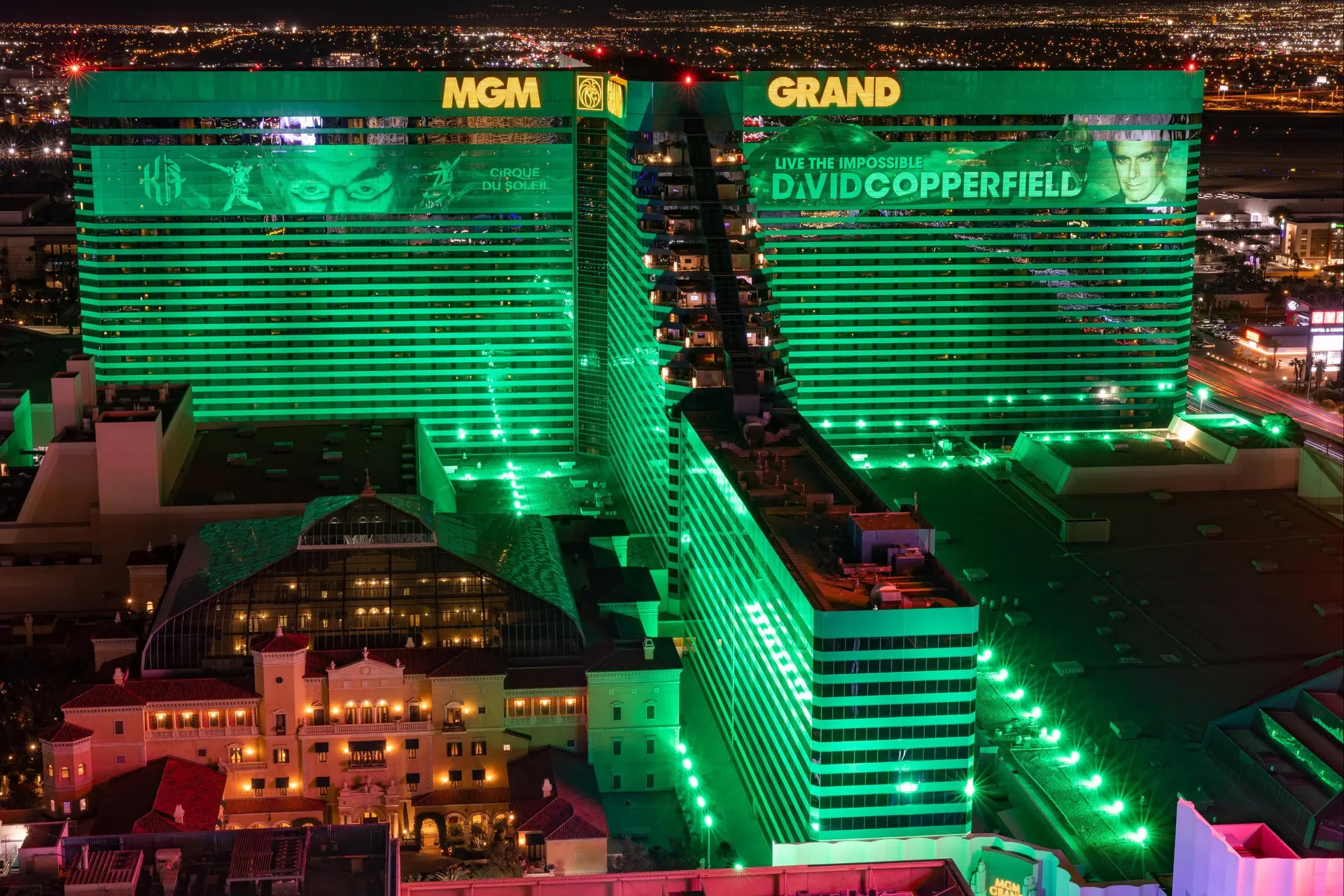 Green lights illuminating the resort building with its company name at the top of the building in large yellow writing