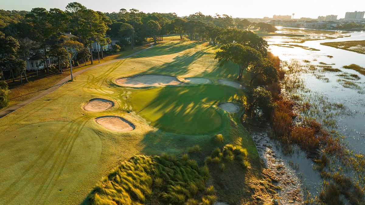 Overhead view of the sun shining onto a smooth green surrounded by sand bunkers