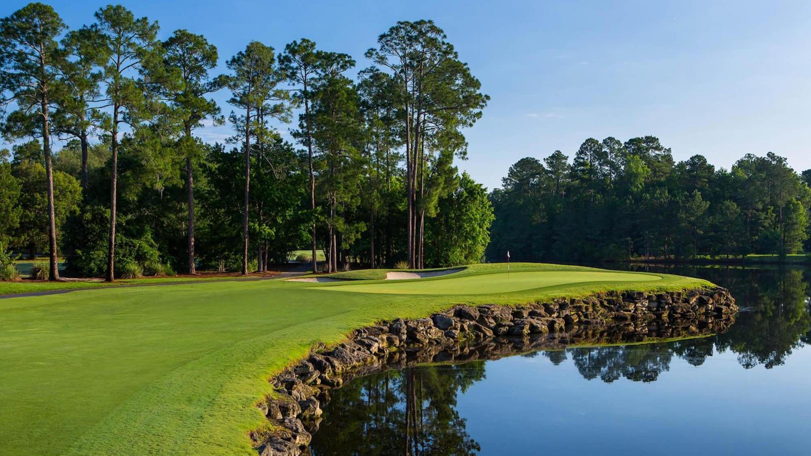Manicured green elevated from water hazard by a stone wall