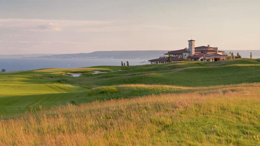 Rolling dunes surrounding a smooth green nestled with bunkers leading to the clubhouse