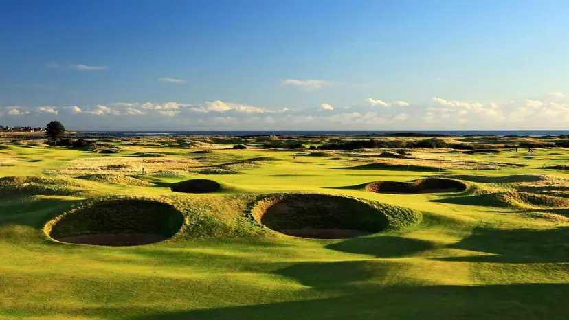 Deep bunkers surrounding well maintained greens under blue skies