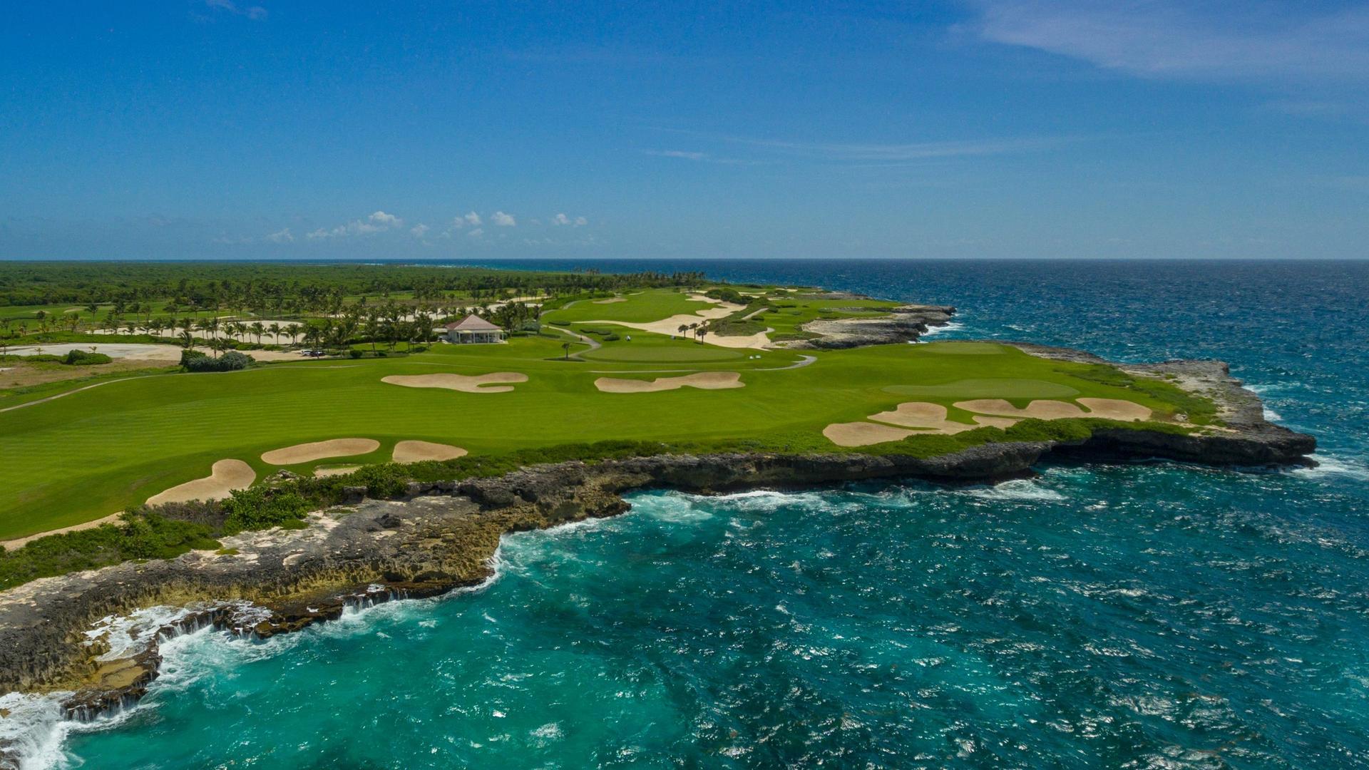 Overhead view of a wide fairway nestled with sand bunkers with coastal views
