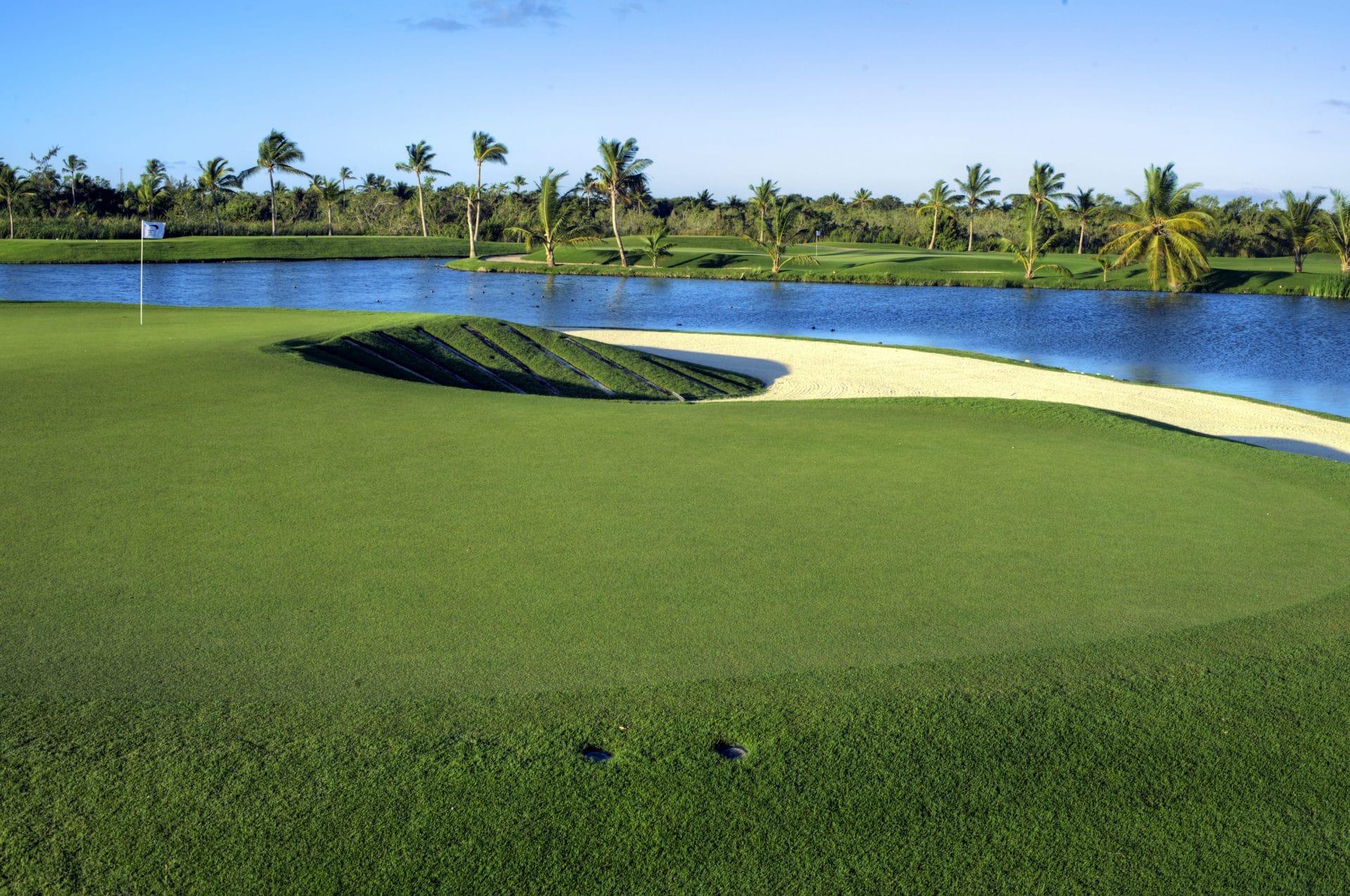 An elevated green surrounded by a sand bunker and water hazard