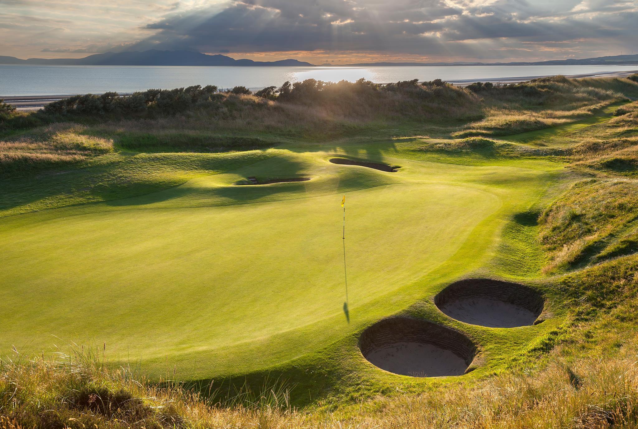 Pot bunkers around the green with the sea in the background at Western Gailes