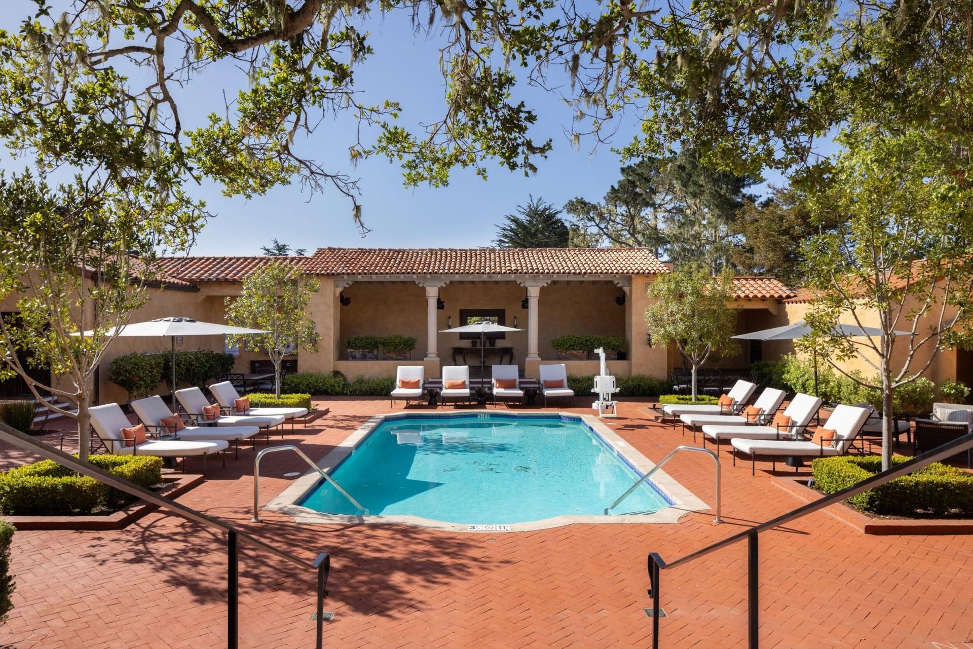 Outdoor swimming pool at the resort surrounded by sunbeds under the Pebble Beach sun