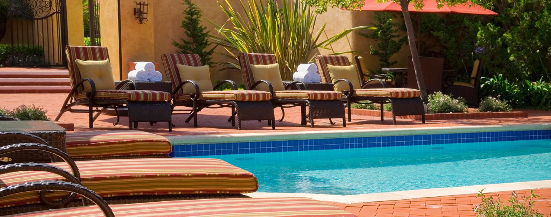 Sunbeds with complimentary towels look over the clear blue outdoor swimming pool