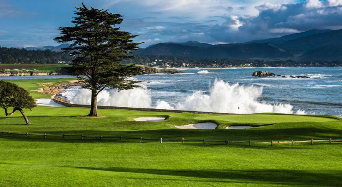 Smooth green surrounded by sand bunkers with the sea crashing into the course