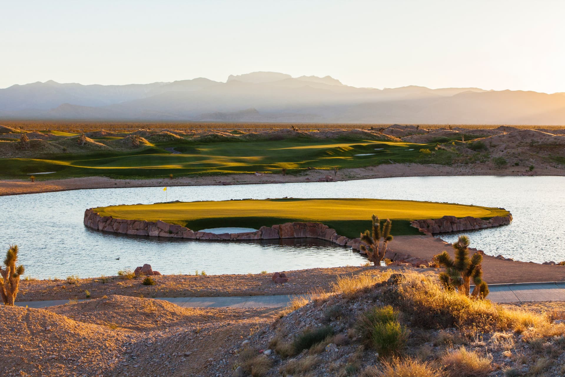 Elevated island like green surrounded by water and a stone path to navigate the course