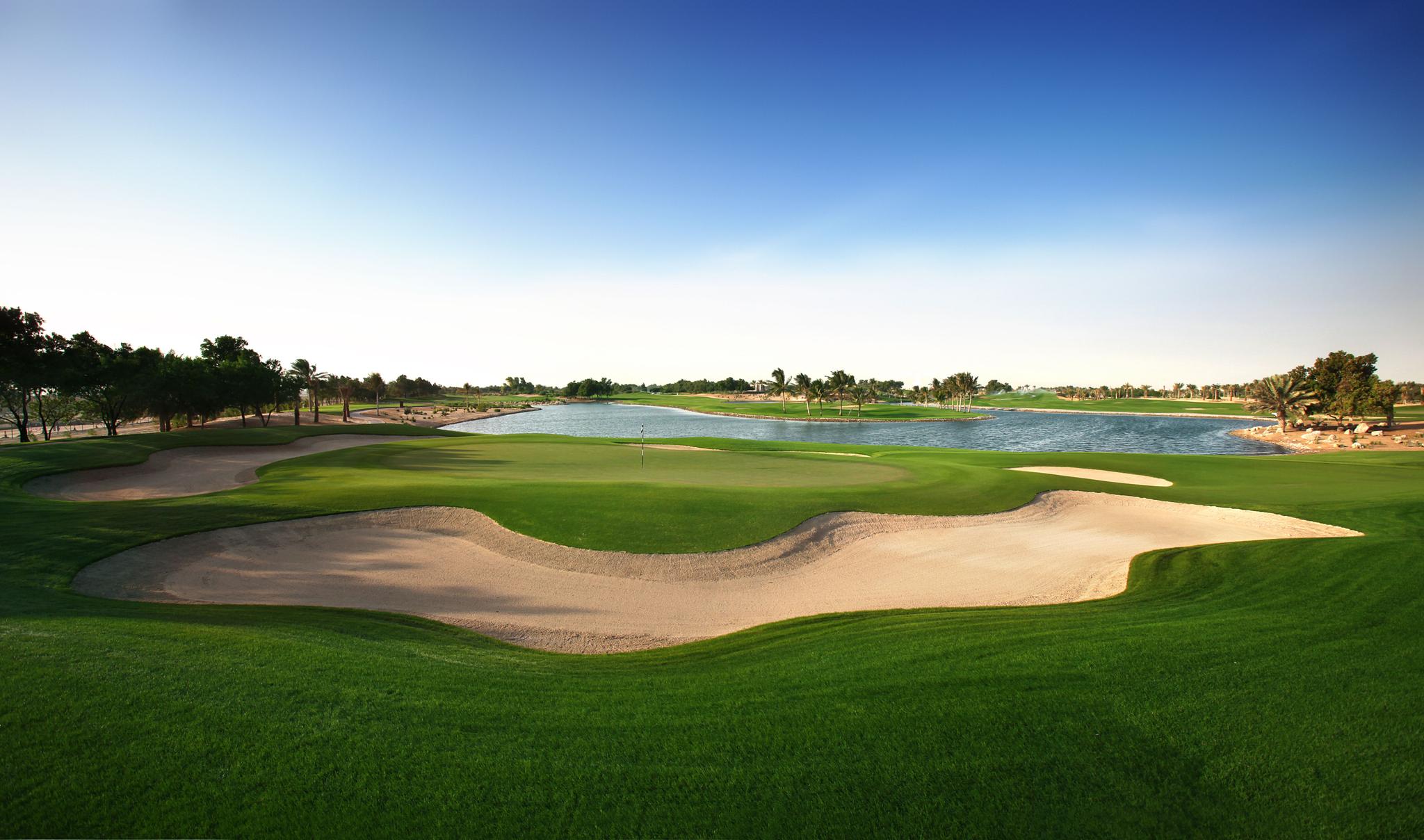 A smooth green surrounded by sand bunkers next to a water hazard