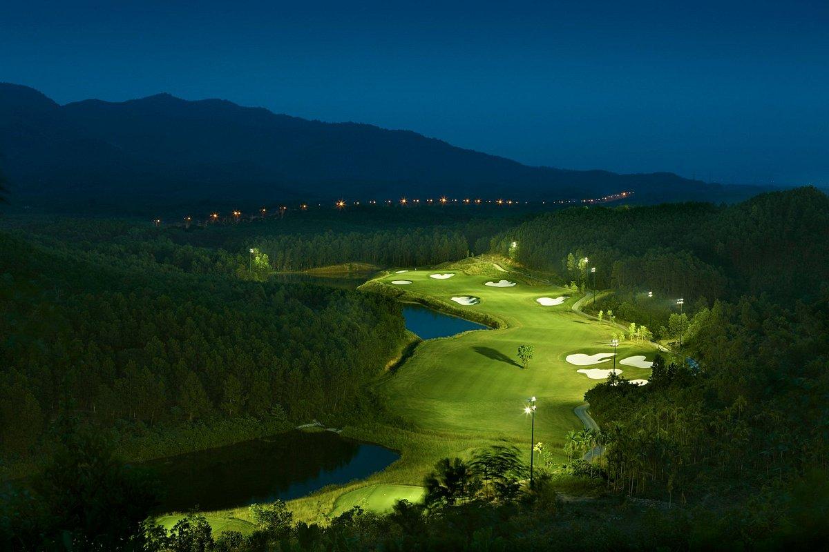 A well maintained fairway nestled with sand bunkers leading to a smooth green being lit up at night by flood lights