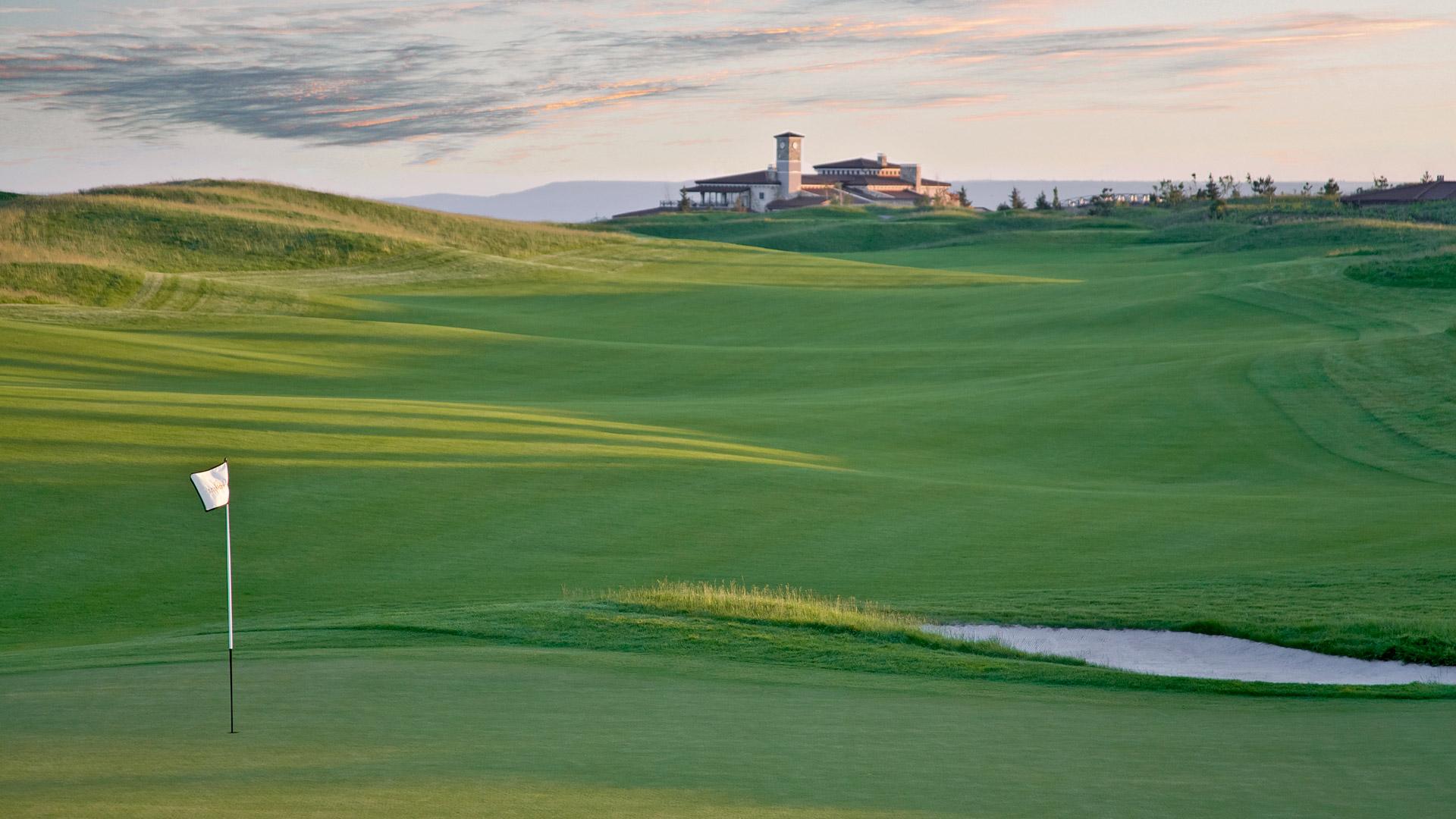 A wide well maintained fairway leading to a smooth green nestled with a sand bunker