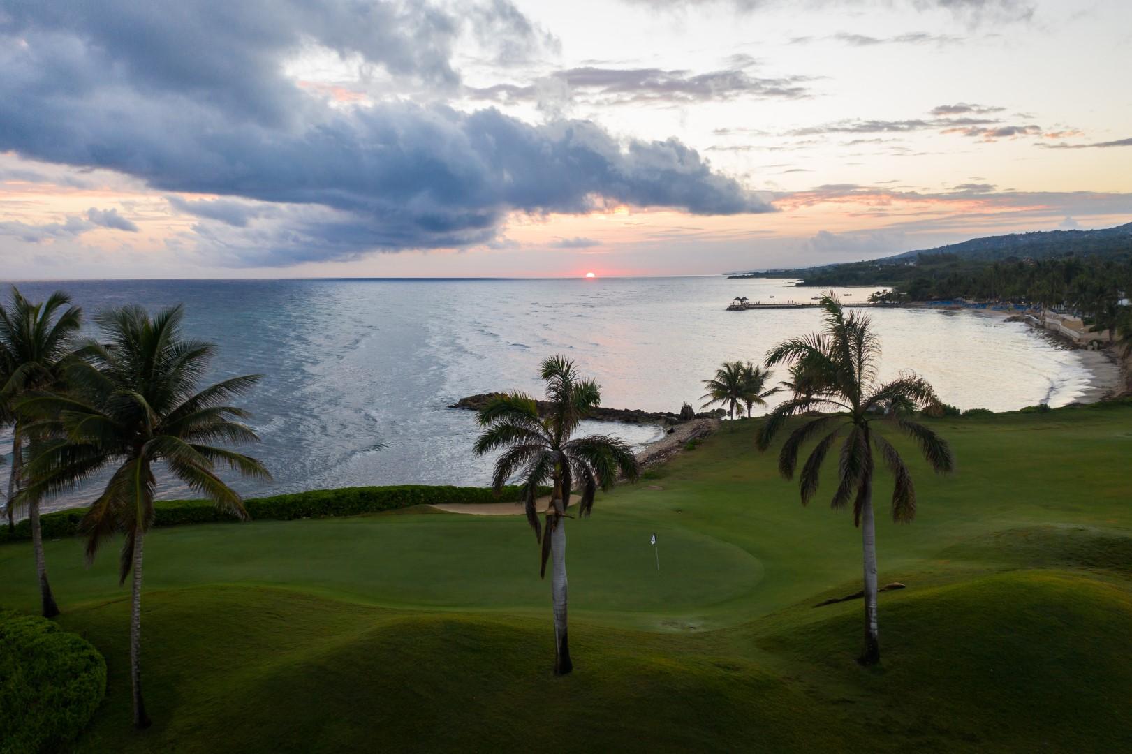 Sunset over a scenic golf course by the sea.