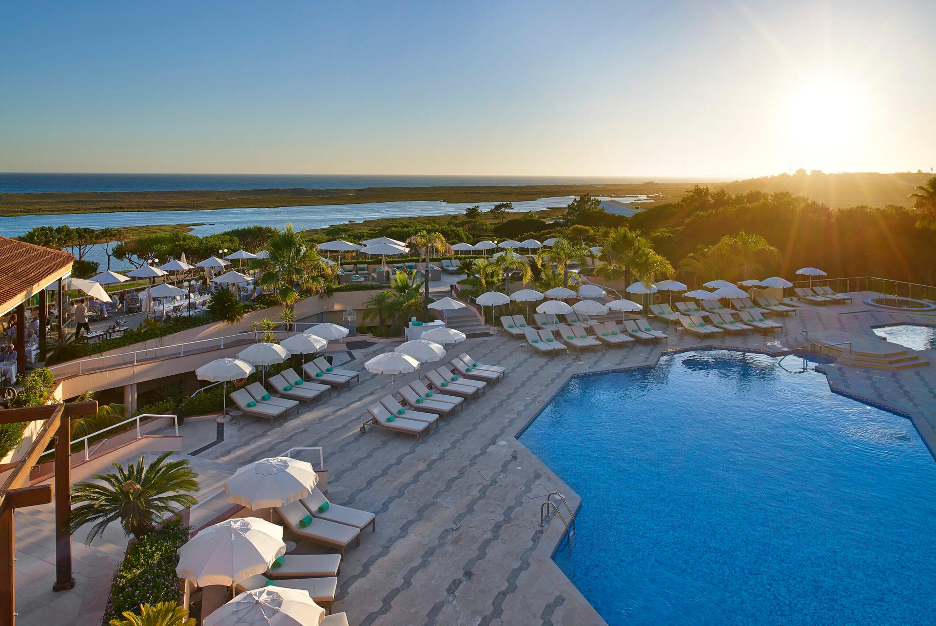 Outdoor swimming pool area with sun loungers at sunset