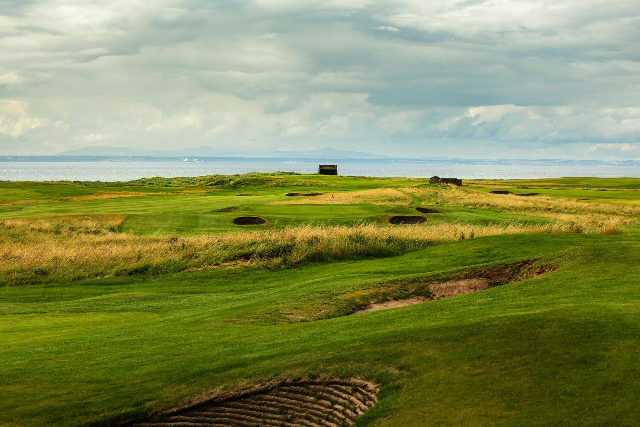 Rolling fairways lined with deep bunkers leading to a green by the sea.