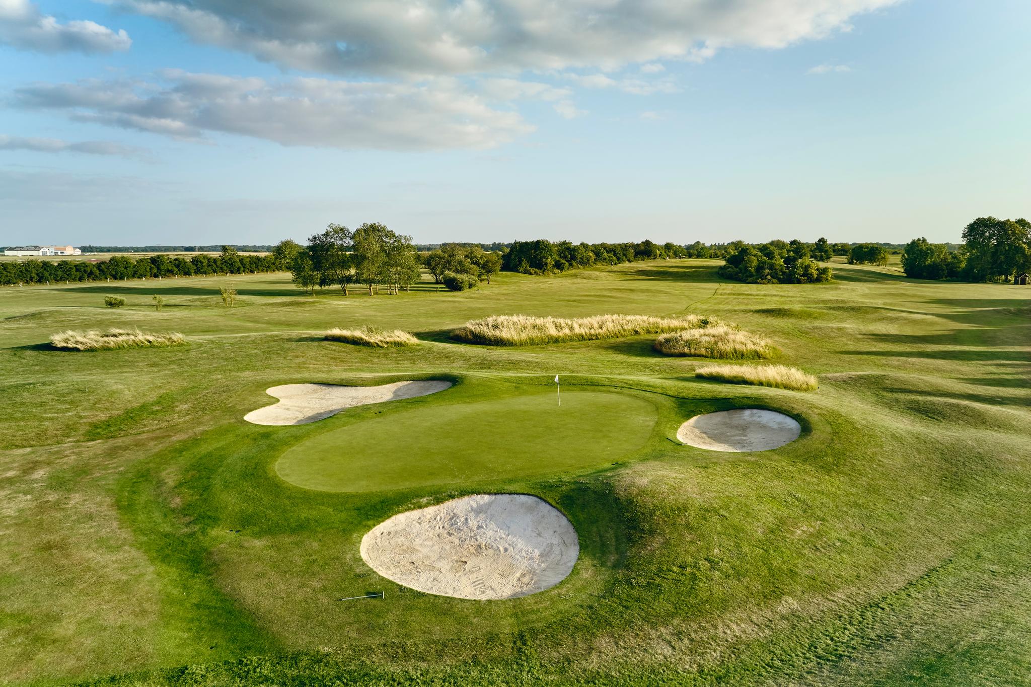 Green surrounded by three bunkers, wide open fairways behind