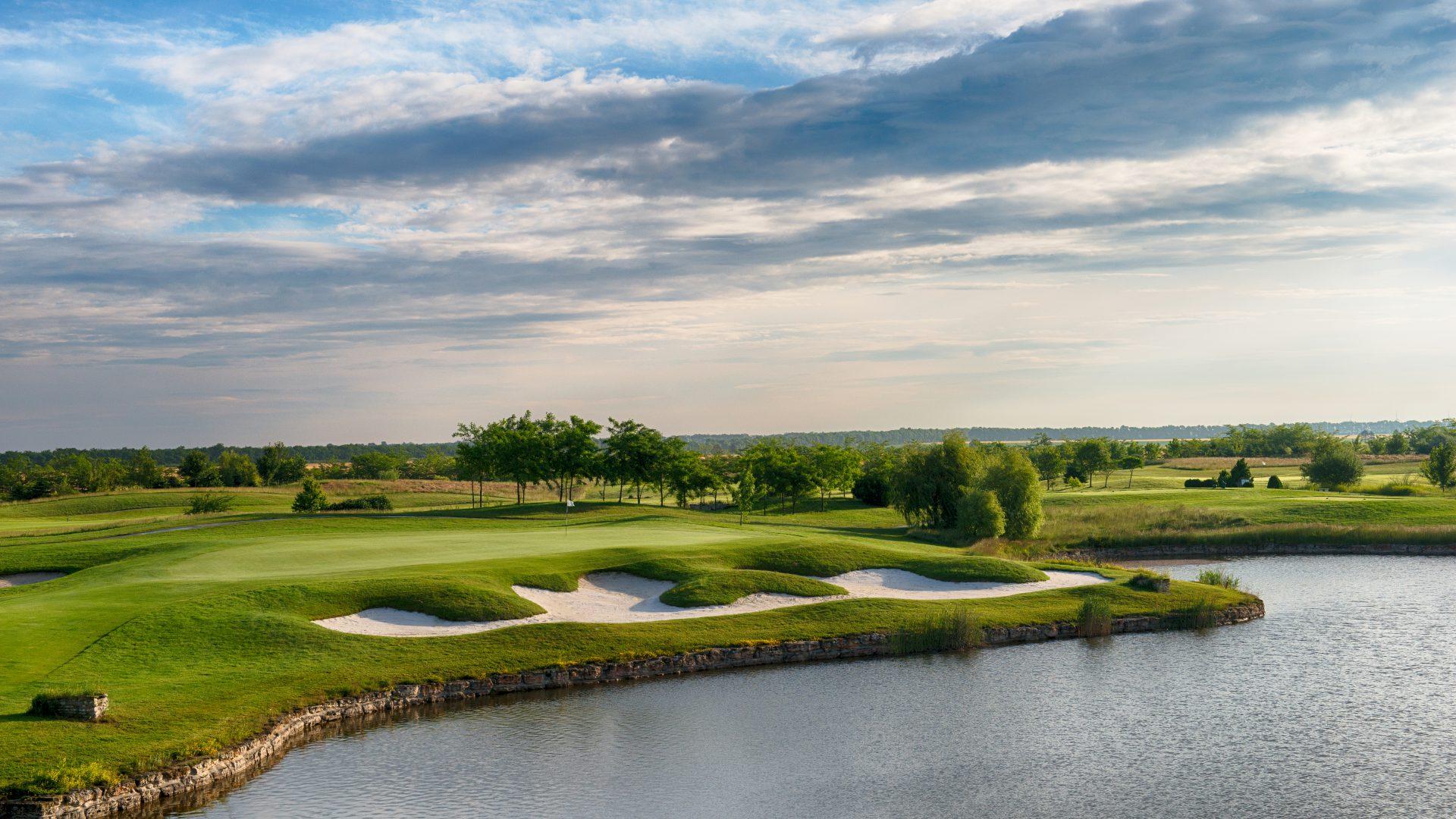 A large sand bunker sandwiched between a well maintained green and a large sand bunker