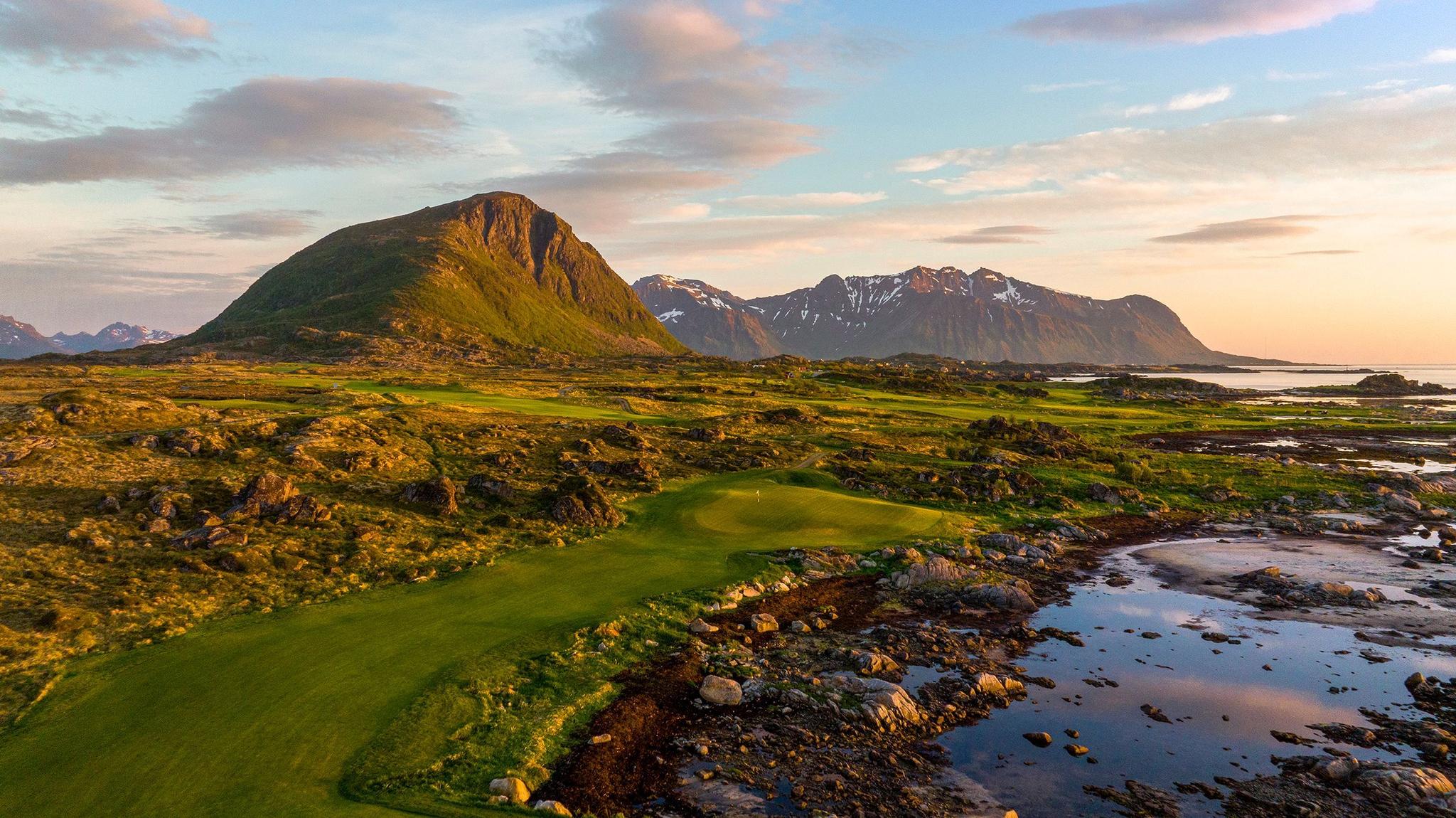 A well maintained fairway leading to a smooth green surrounded by a rocky rough