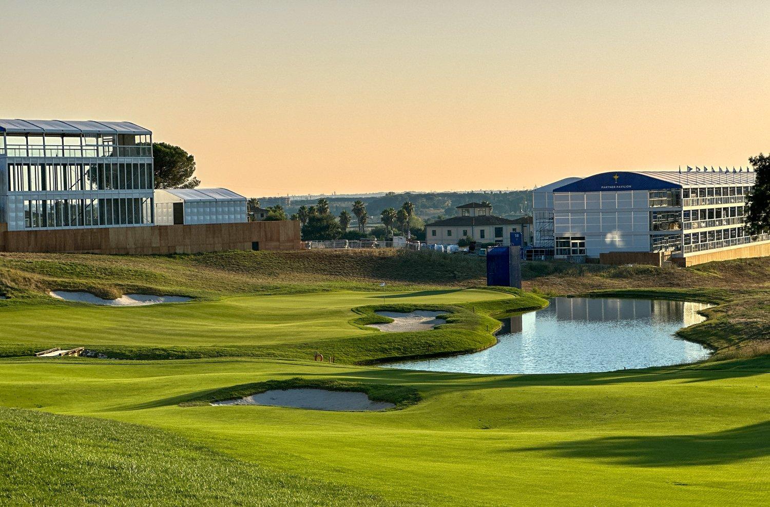 A smooth green nestled with sand bunkers strategically placed next to a water hazard