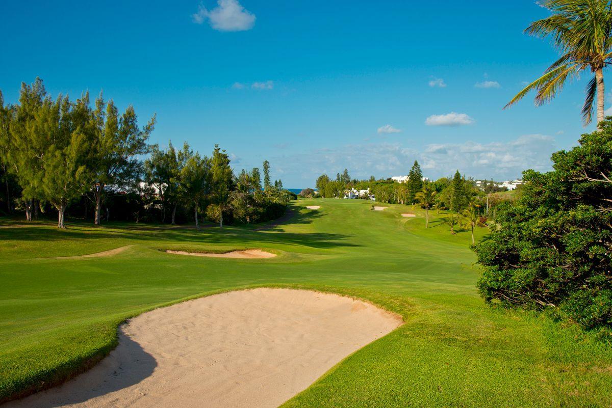 A wide, open fairway lined with trees and bunkers stretches out toward the horizon.