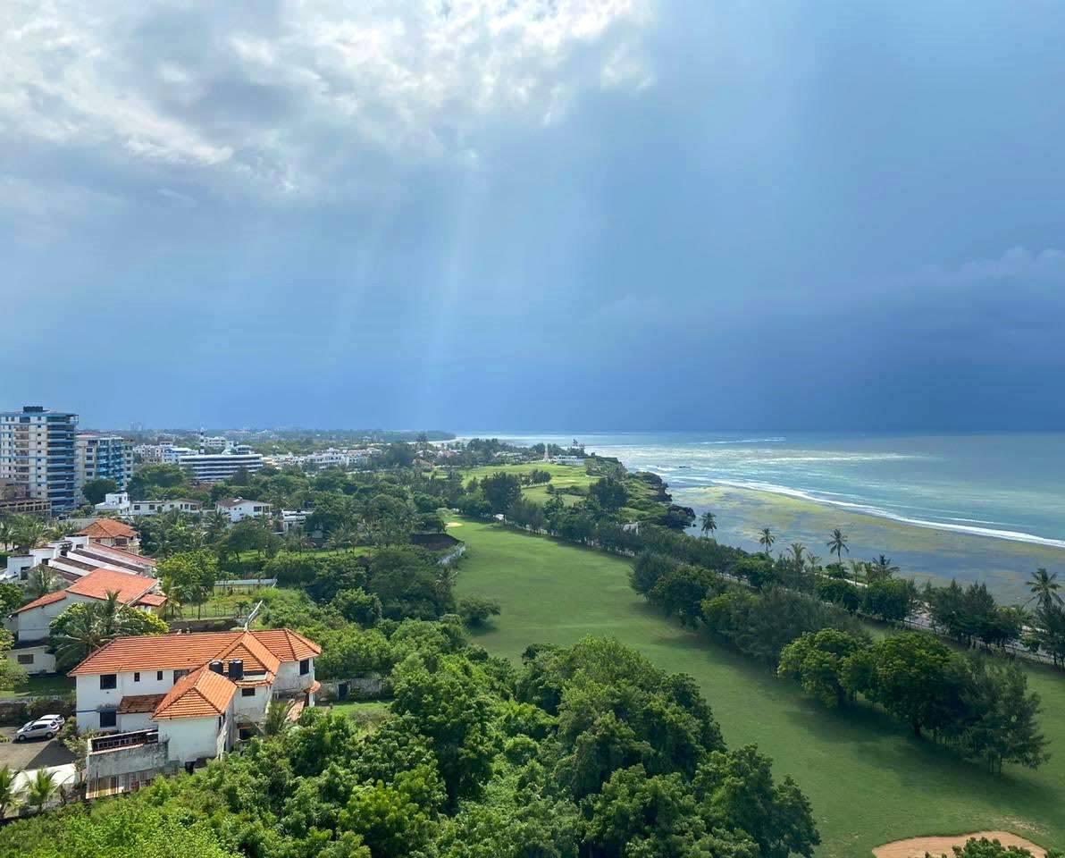 A coastal golf course with ocean views and nearby buildings.