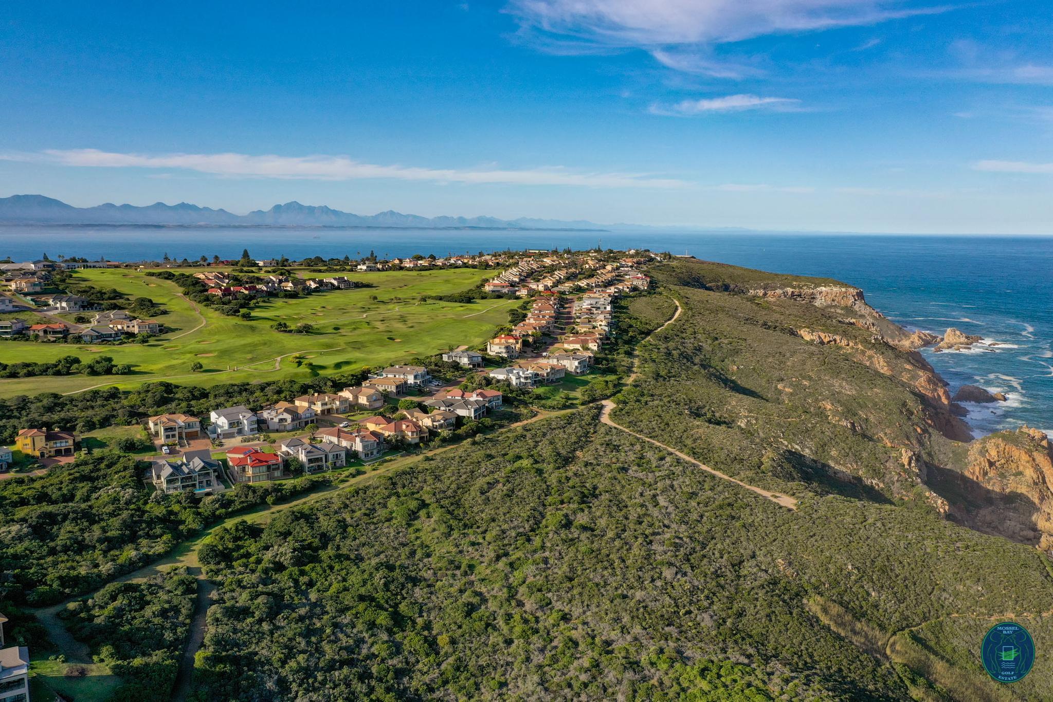 Aerial view of Mossel Bay Golf Club with homes overlooking the ocean.
