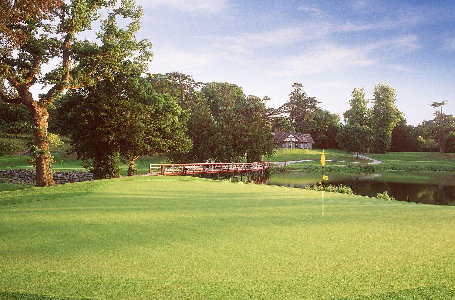 A putting green beside a pond with a classic red bridge backdrop.