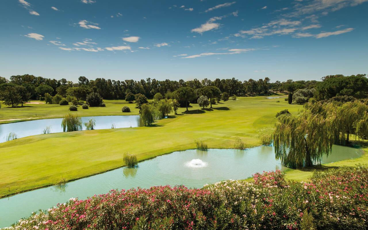 A wide view of a golf course with multiple ponds and beautiful landscaping.