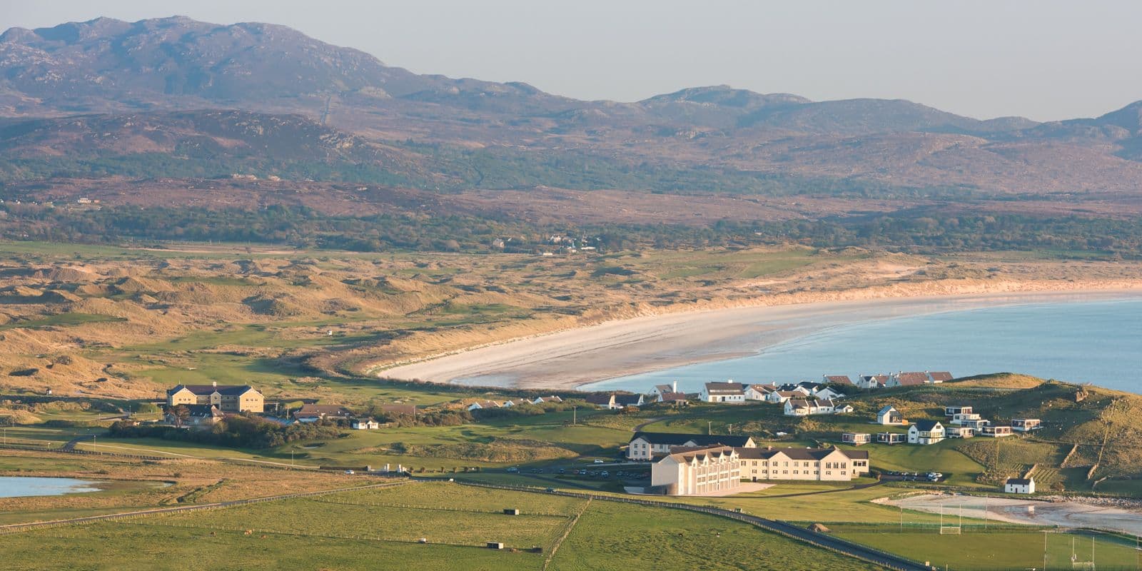 Aerial view of the resort, golf course, beach and mountains in the back