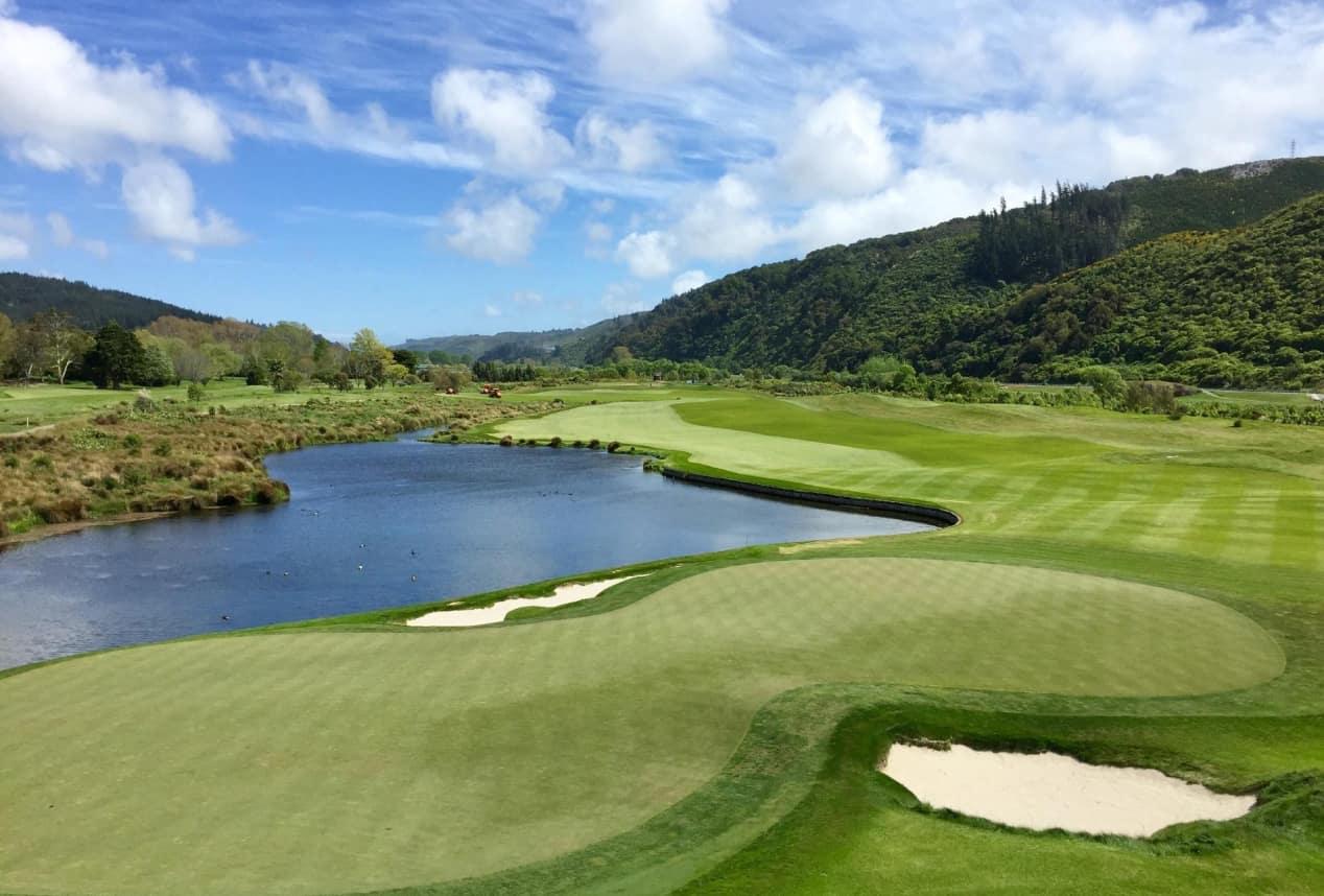 A winding fairway leading to a smooth green next to a large water hazard