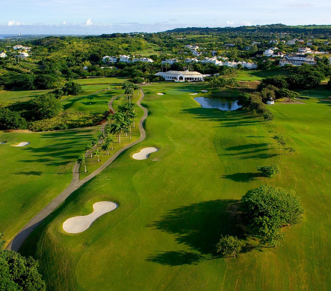 Aerial view of a pristine golf course lined with palm trees and winding paths.