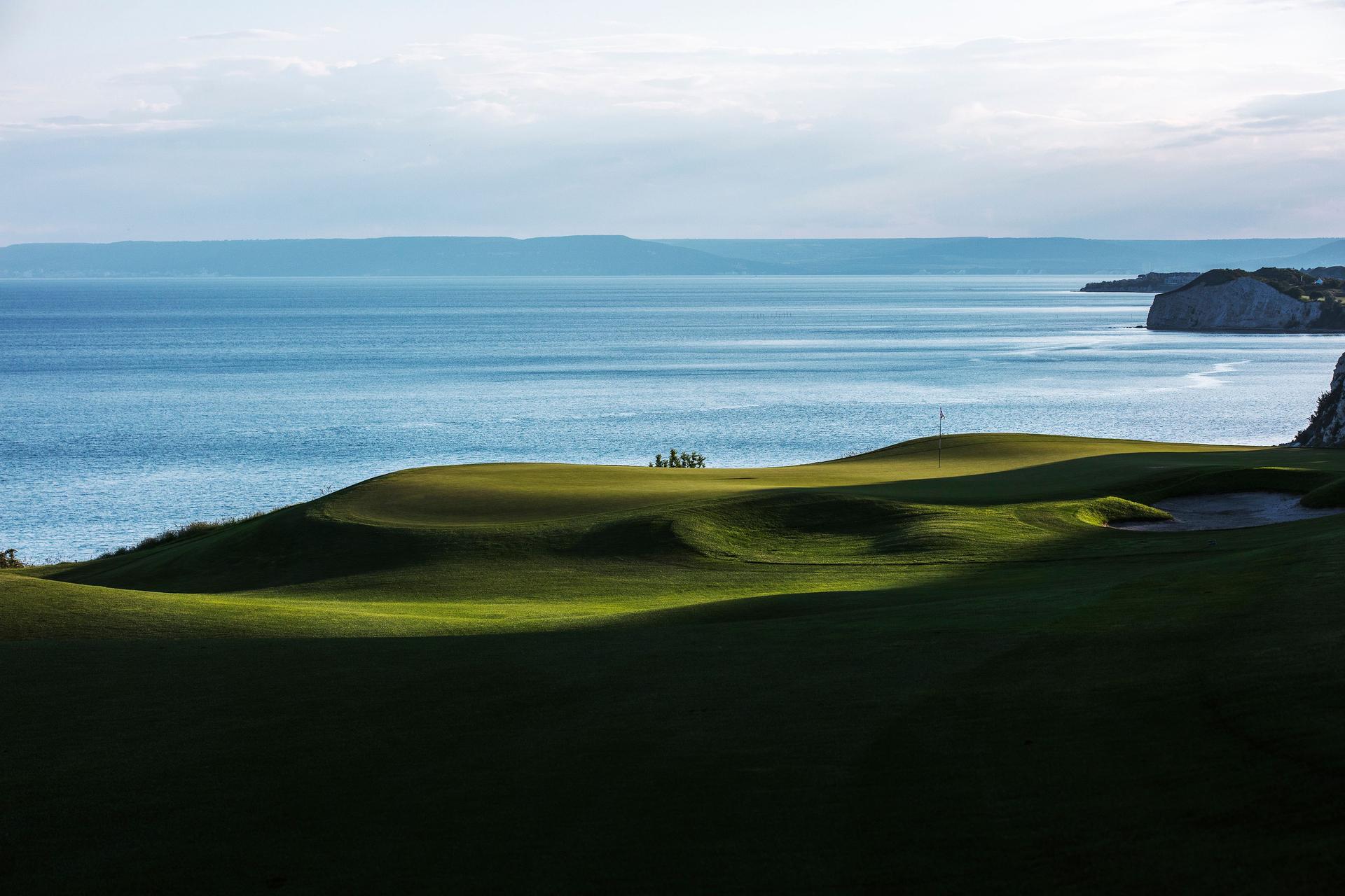 A smooth green with coastal views and the above mountain shadowing over
