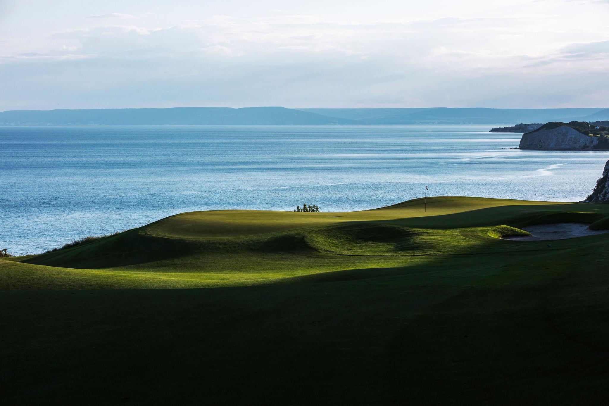 A smooth green with coastal views and the above mountain shadowing over