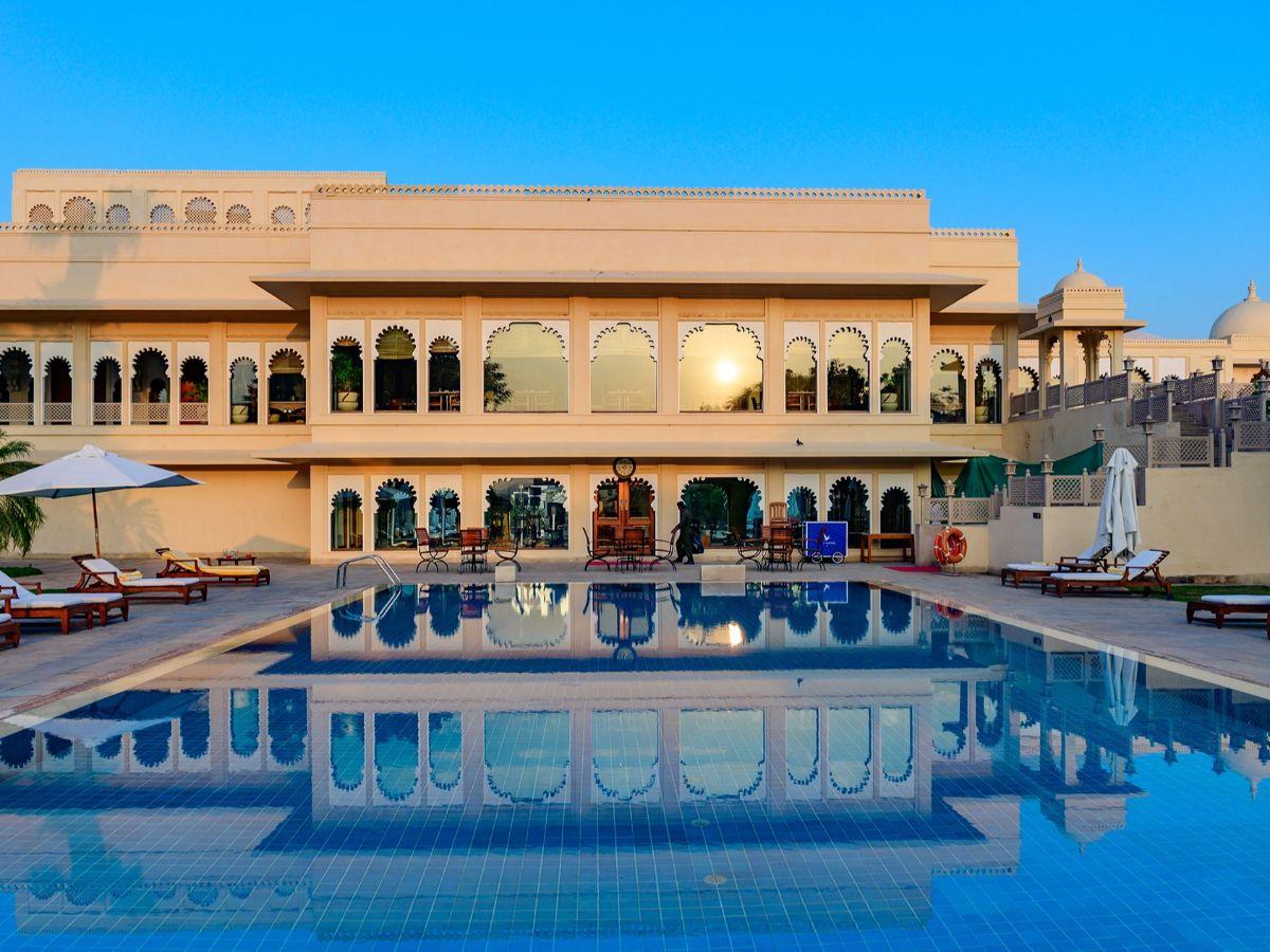 Outdoor swimming pool surrounded by sunbeds at the Trident Hotel at sun set