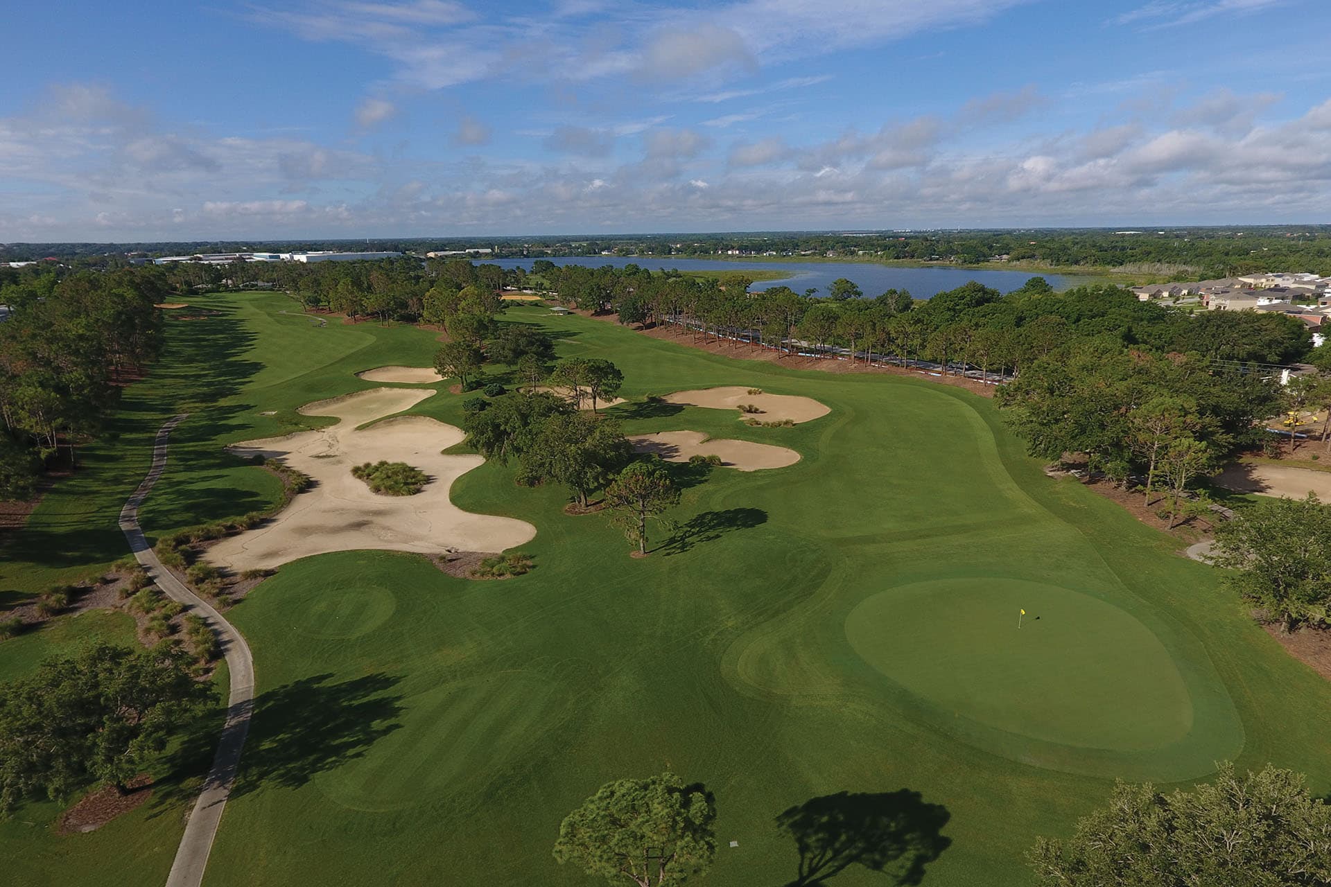 Birdseye view of a wide fairway littered with sand bunkers leading to a smooth green