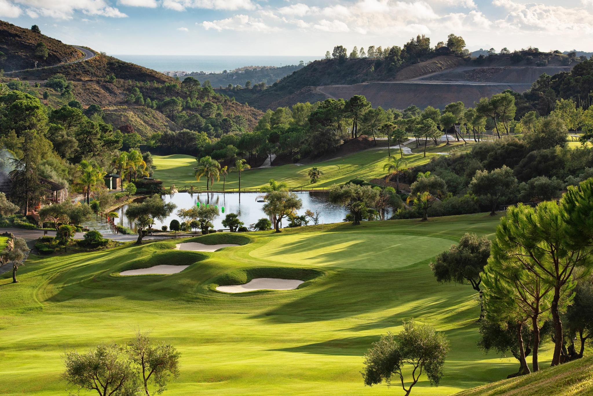 Overhead view of a well maintained fairway leading to a smooth green surrounded by sand bunkers