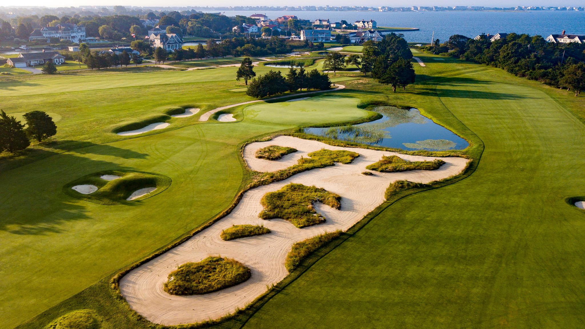 Overhead view of manicured fairways running parallel with a large sand bunker in the centre