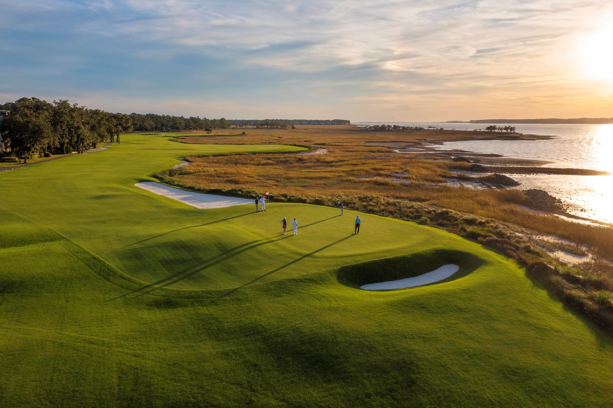 Overhead view of golfers enjoying their round on a manicured green with coastal views