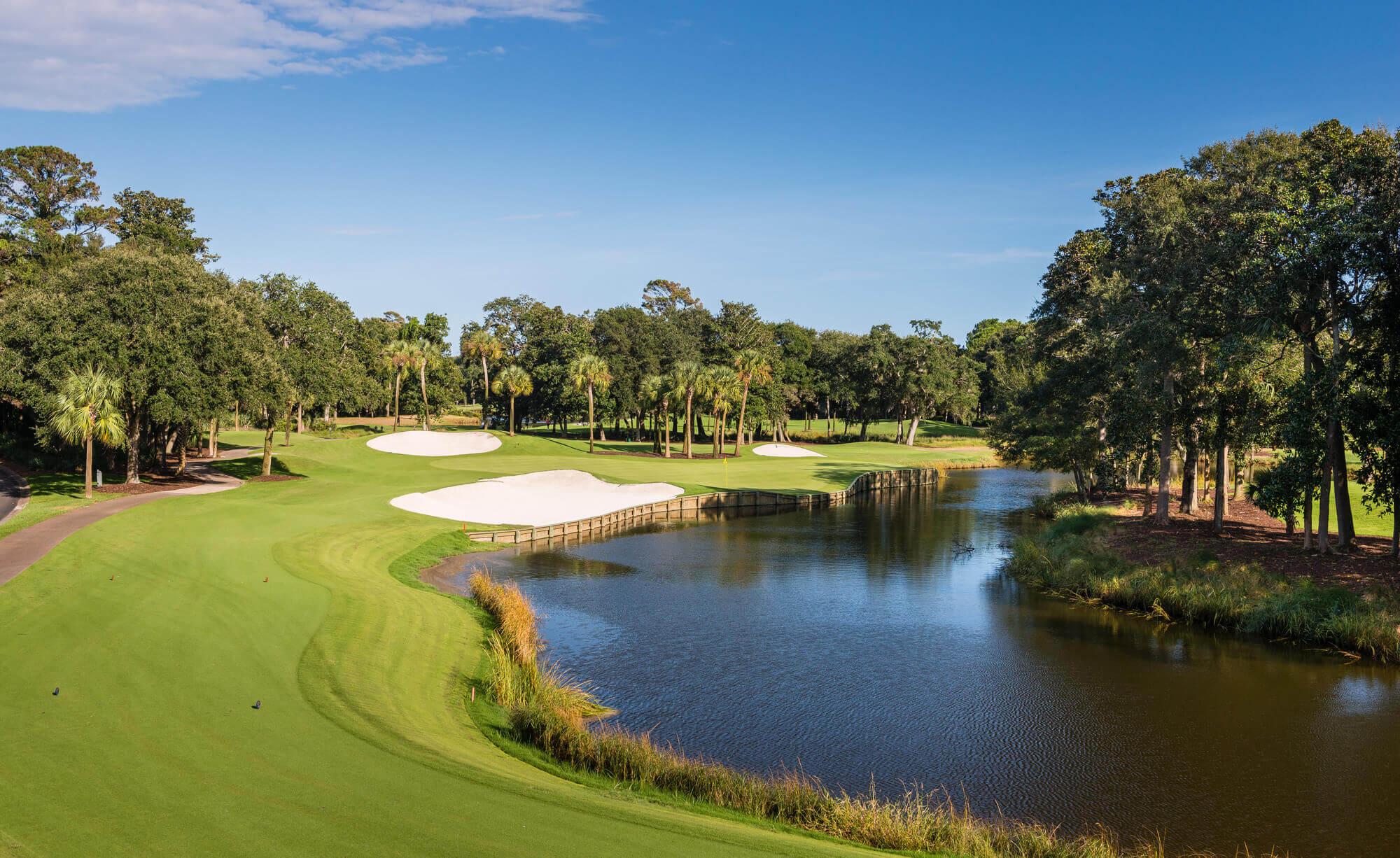 Winding fairway running along a river leading towards a well-maintained green at the course