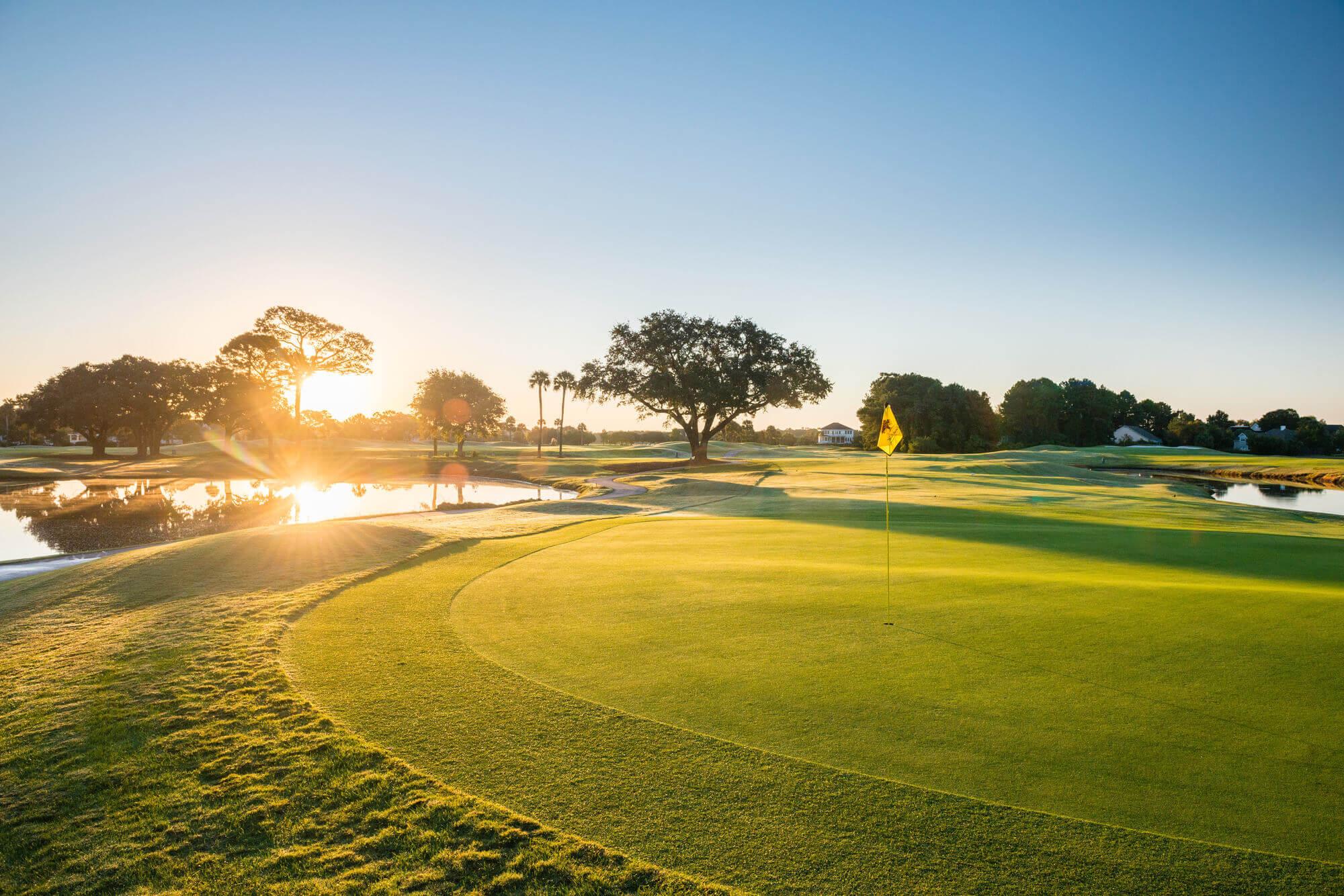 Sun set reflecting of a water hazard next to a manicured green at the Oak Point course