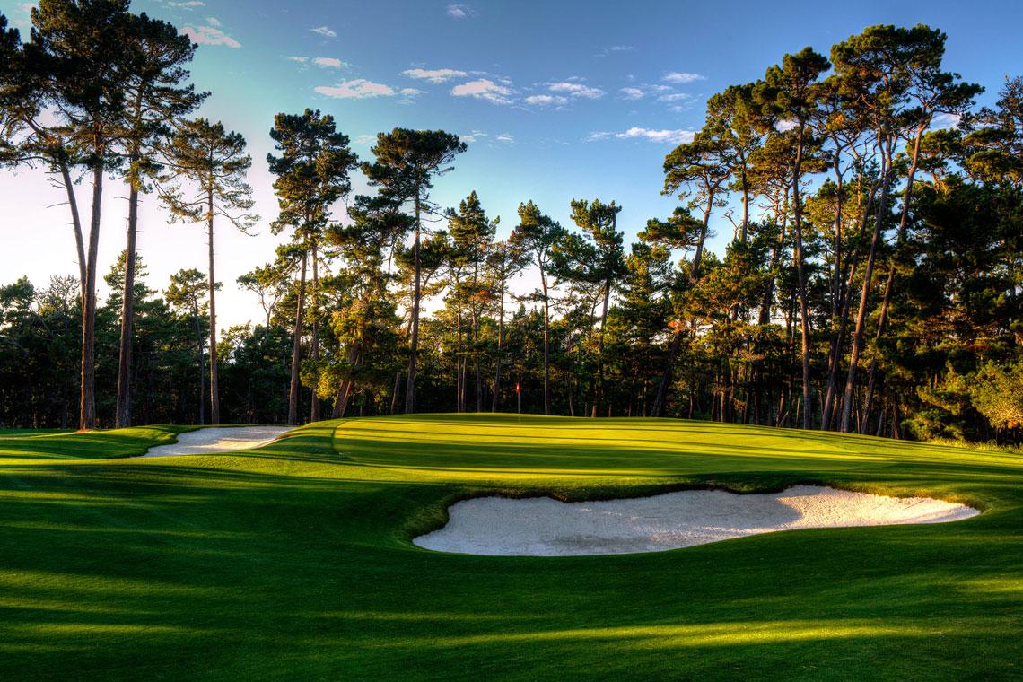 Sand bunkers and tall trees surround a well-maintained green