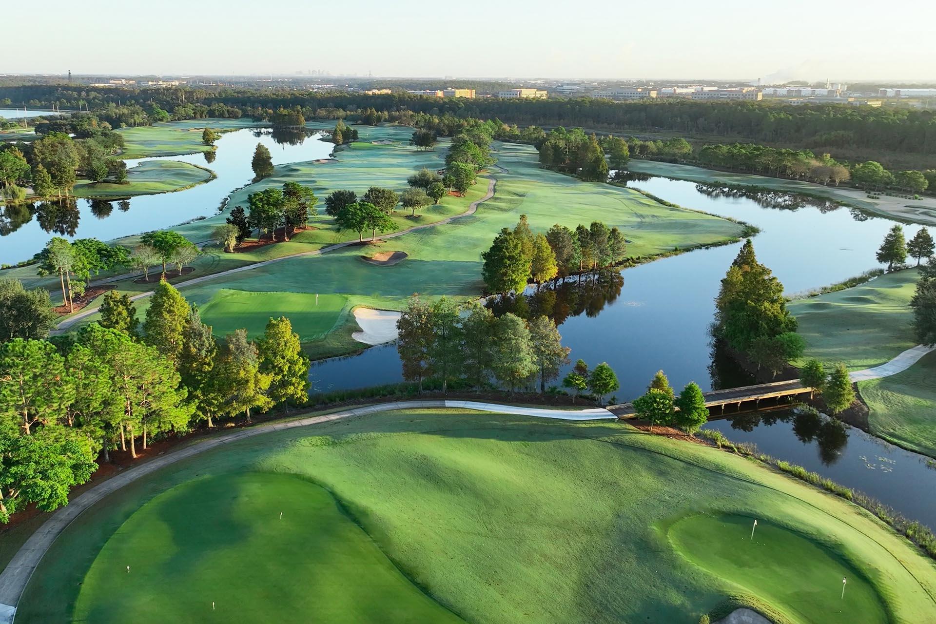 Aerial view of winding fairways and lakes surrounded by lush greenery.