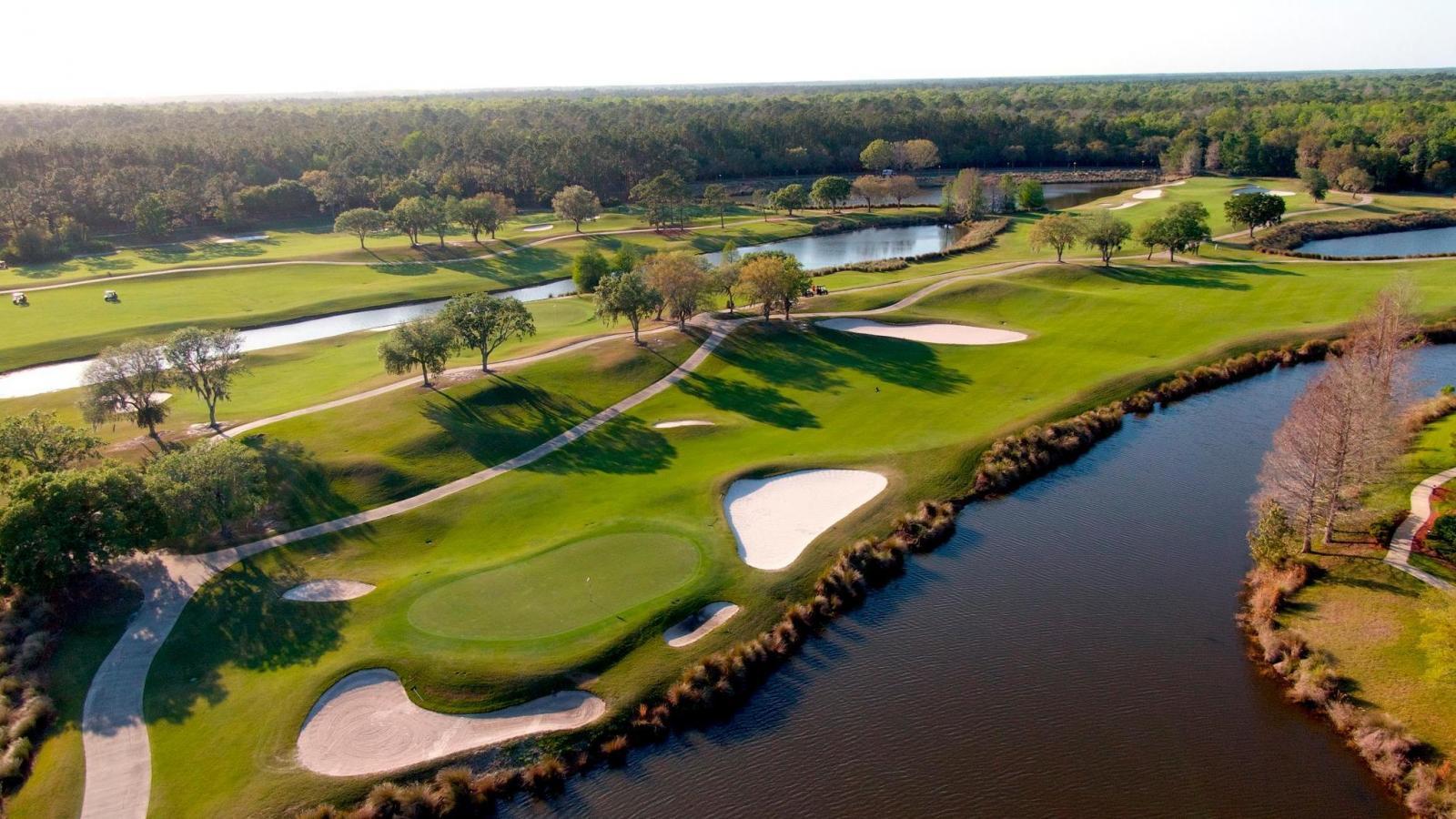An aerial view showcases a sprawling golf course with multiple fairways, greens, and water hazards.