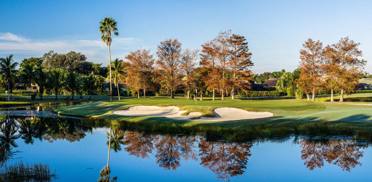 Panoramic view of a unique sad bunker sandwiched between a green and water hazard which reflects the trees