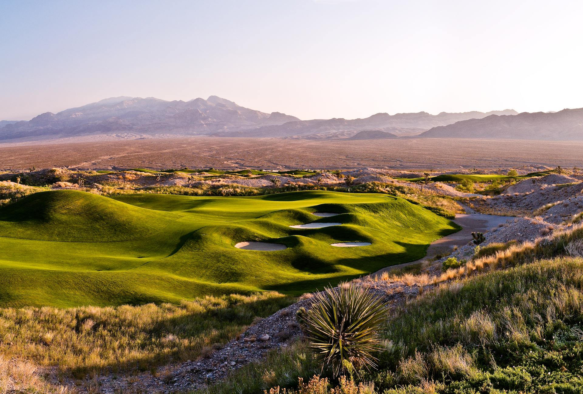 Rolling dunes and winding fairways leading to a smooth green with mountain views