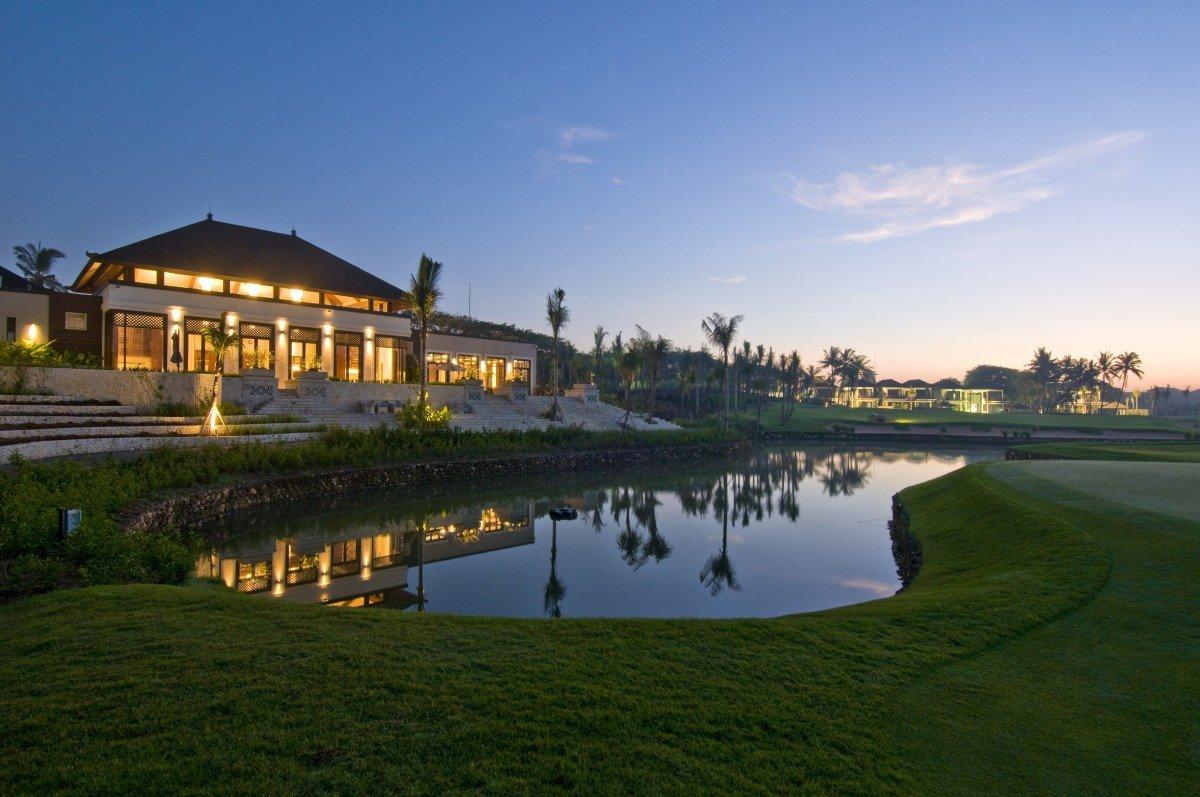 The Bali National Golf Clubhouse beautifully lit at dusk, reflecting on a calm pond.